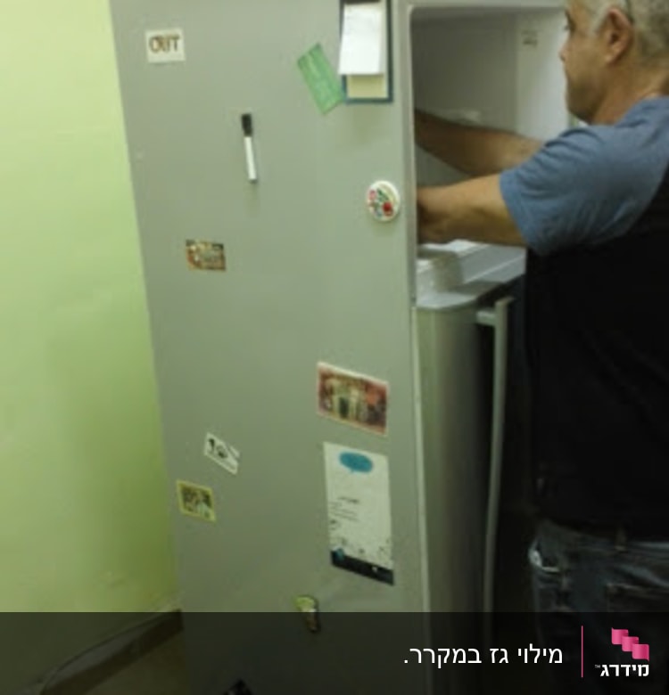 אדם מתקן מקרר עם כלים וחלקים